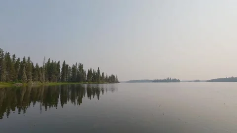 View from the front of a canoe while it moves forward across a calm northern Stock Footage 323539218