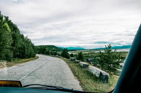 View from front window of auto car on asphalt broken suburban road of highway Stock Photos