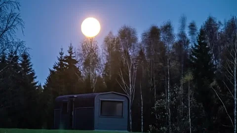 View of full moon over a cabin in the forest, Latvia. Video stock 340639125