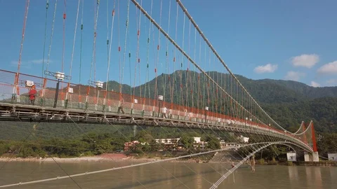 View of Ganga river in Rishikesh. People crossing Ram Jhula bridge. Stock Footage 117910424