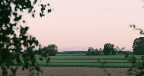 View from the garden threw the trees to the Mountains Alps Bavaria sunrise 4K Stock Footage 310577148