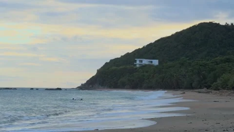View of gentle ocean waves rolling onto a tropical sandy beach with a lush Stock Footage 341684664