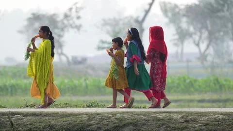 View of girls walking with carrots in a rural field, Bangladesh. Video stock 335586355