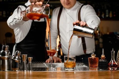 View of glasses into which two professional bartenders are pouring different 스톡 사진