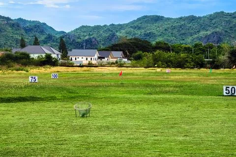 View of golf driving range with grassy slopes and distance signs with beaut.. Stock Photos