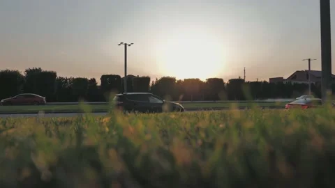 View from the gound through the blurry green grass on a city road with traffic Stock Footage 201250603