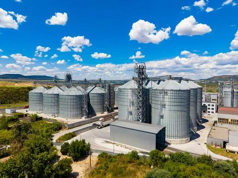 View of grain storage silos under bright blue sky with clouds during daytime Stock Photos