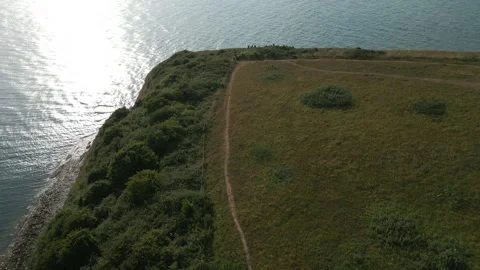 A view of a grassy hillside with a path leading down to the water Stock Footage 298272441