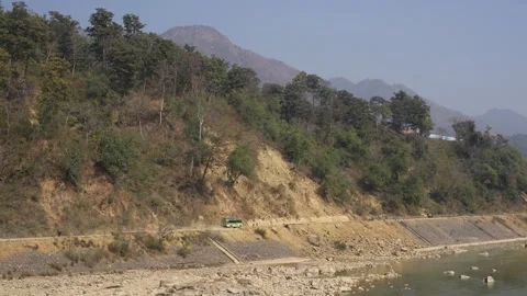 View of a green bus driving on a mountain road by a river, Nepal. Vídeo Stock 335604279