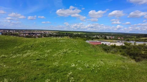 View of a green landscape with clouds and houses in the distance on a clear day Vídeo Stock 340448296