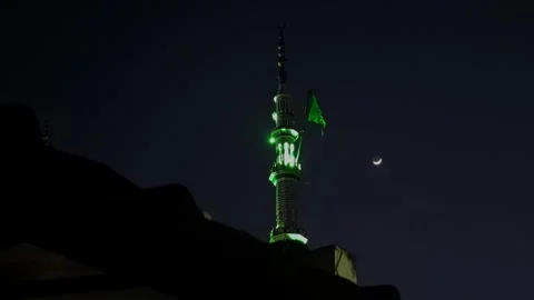 View of green laser beams lighting night sky above mosque with half moon gl.. Video stock 335872560
