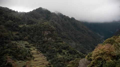 View of a green valley with terraces surrounded by cloud-covered mountains. Stock Footage 301718648
