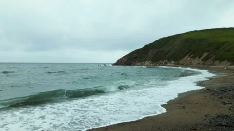 View from the ground of the waves crashing on the beach with pebble Stock Footage 162623875