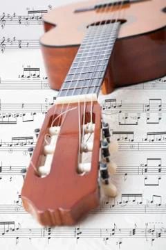 View of a guitar and its strings with musical notes from a sheet music. Stock Photos