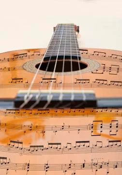 View of a guitar and its strings with musical notes from a sheet music. Stock Photos