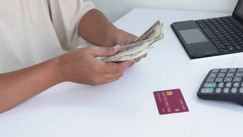 A view of a hand counting dollar bills with a credit card on a table. Stock Footage 338170069