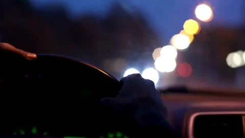 View of a hand holding the steering wheel of a car while driving at night. Stock-Footage 336265405