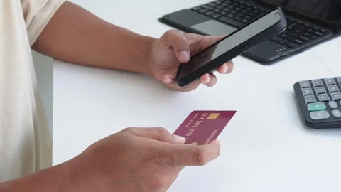 A view of a hand making a transaction with a credit card and a smartphone. Stock Footage 338170071