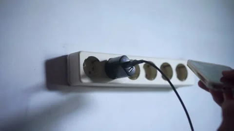 View of hand plugging cell phone charger cable into wall socket. Stock Footage 322159482