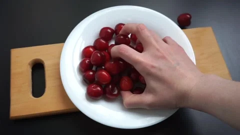 View hand takes a handful of cherries, red berries in a white plate Stock Footage 244382817
