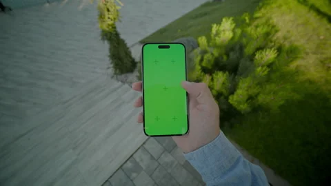 View on hands holding and scrolling vertically phone with green screen. On Stock Footage 278238900