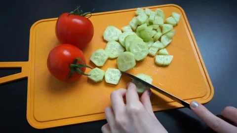 View of hands with a knife cutting a cucumber on a kitchen cutting board. Food Stock Footage 244295942