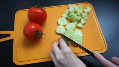 View of hands with a knife cutting a cucumber on a kitchen cutting board Stock Footage 244989081