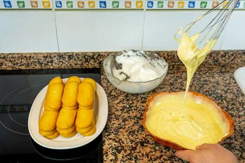 View of hands preparing the cream to make a Tiramisu cake in the kitchen at h Stock Photos