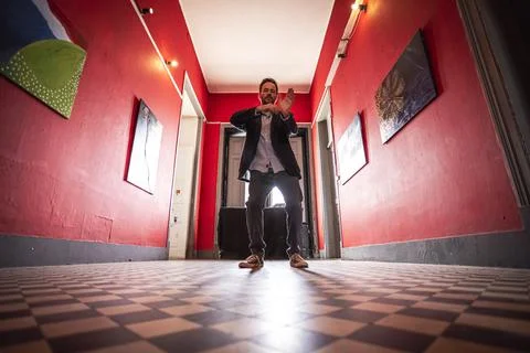 View of a handsome guy dancing along in an empty hallway wearing an elegant j Stock Photos