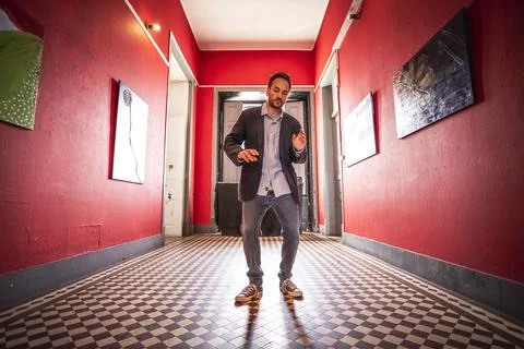 View of a handsome guy dancing along in an empty hallway wearing an elegant j Stock Photos