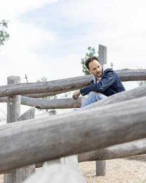 View of an handsome guy sitting alone in a public park wearing casual outfit  Stock Photos