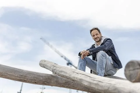 View of an handsome guy sitting alone in a public park wearing casual outfit  Stock Photos