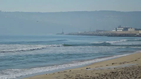 View of the harbor and mountains from the seashore. Waves crashing against the Stock Footage 304878206