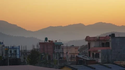 View of hazy mountain peaks and urban rooftops at sunset, Nepal. Vídeo Stock 335607477