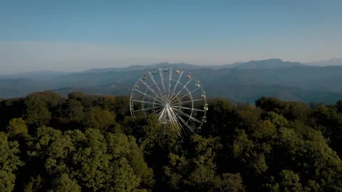 View from a height of 4k. The Ferris wheel rotates on the top of the mountain Vidéo 163207145