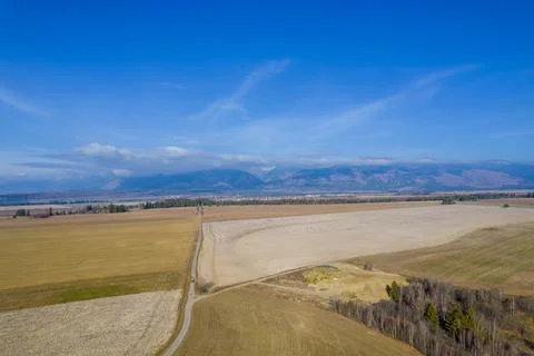A view from a height of the autumn fields, surrounded by high mountains. Fog  Stock Photos