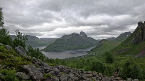 View of hiker on rocky trail overlooking fjord and village in Senja Norway Vidéo 342059387
