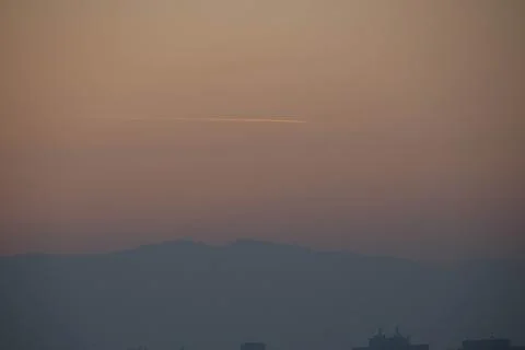 View of a hill during sunset with trace of plane Stock Photos