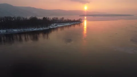 View of the hills by the river at sunset. Orange sun over my river. Snow lies on Stock Footage 233937776