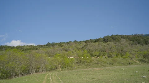 A view of the hilly landscape and the blue sky, with a distant herd of goats on Stock Footage 272339616