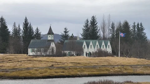 View Of Icelandic Flag Flapping in Wind Next To Old Church, Iceland Stock Footage 97259935