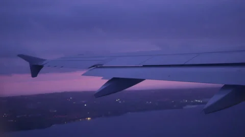 View from illuminator on airplane wing over the water and land at sunset - 4K Stock Footage 179876253