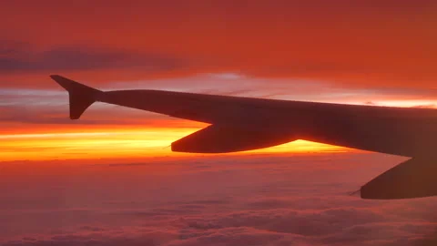 View from illuminator on airplane wing over the clouds at scenic sunset - 4K Stock Footage 196261864