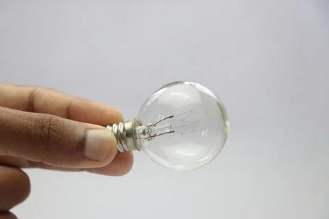 View of incandescent bulb with screw type base held in the hand Stock Photos