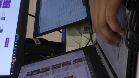 View of an individual working on two laptops and a PC for collecting data Stock Footage 166082915