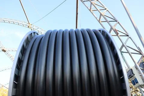 A view of an industrial cable reel positioned against a backdrop of a clear blue Stock Photos