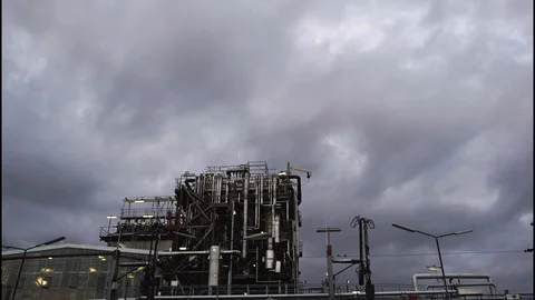 A view of an industrial facility at dawn with clouds in the background. Stockbeeldmateriaal 86557000
