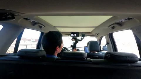 View inside a car from behind of a man filming his friends on a road trip in 4k Video stock 155775704