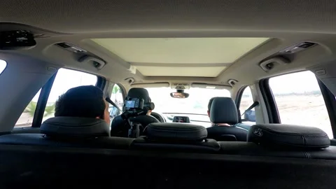 View inside a car from behind of a man filming his friends with a camera on Stock Footage 155777305