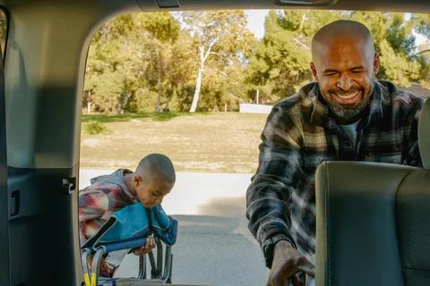 View from inside the car of dad smiling grabbing ice chest from trunk of the car Stock Photos
